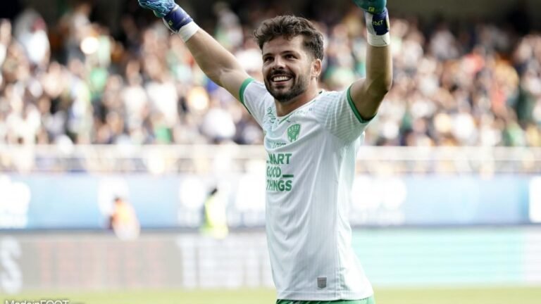 Gautier Larsonneur, gardien de but de l'AS Saint-Étienne, en pleine action réalisant un arrêt spectaculaire lors d'un match de football professionnel.