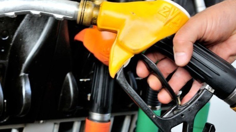 Pompe à essence, chariot de supermarché et usine, illustrant l'impact quotidien et généralisé de la hausse des prix du pétrole sur le coût de la vie et l'industrie.